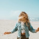 girl in blue denim jacket standing on beach during daytime